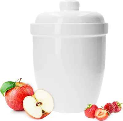 A white ceramic pot with a lid, surrounded by apples and berries.