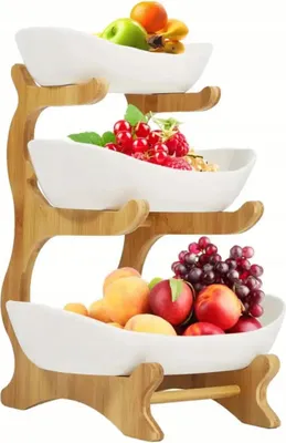 A three-tiered fruit stand made of bamboo with white ceramic bowls filled with various fruits.