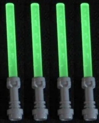 Four green lightsabers with gray handles against a black background.
