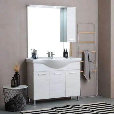 A bathroom vanity set with a sink, mirror, and cabinet, displayed in a room setting with decorative items and a rug.