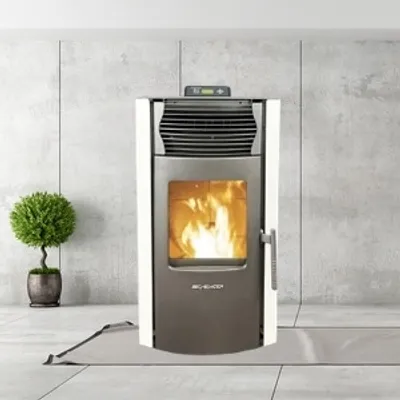 A modern pellet stove is shown in a clean, minimalist room with a concrete wall and tiled floor. A small potted plant is to the left of the stove.