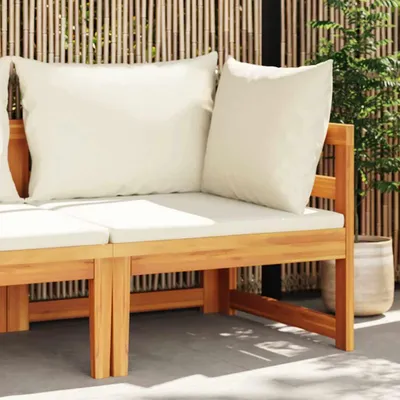 A wooden outdoor sofa with cream cushions against a bamboo screen.