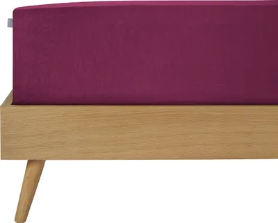 A close-up view of a bed frame with a purple fitted sheet.