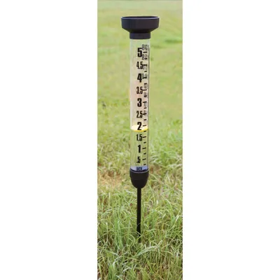 A rain gauge is placed in the grass.