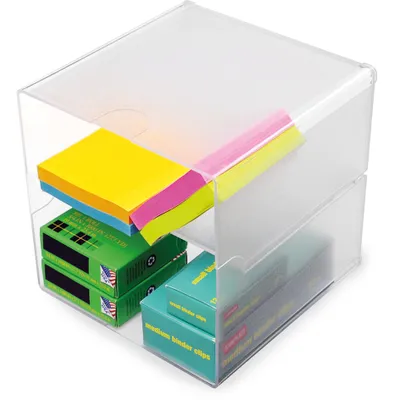 A clear plastic organizer box containing stacks of sticky notes and boxes of binder clips.