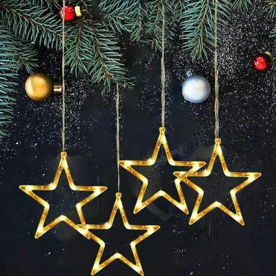 Christmas decorations hanging from a pine branch, including star-shaped lights and ornaments.