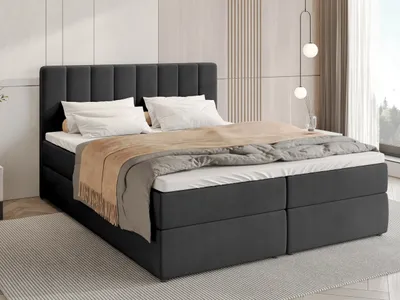 A dark gray upholstered bed with white pillows and a brown throw blanket, set in a modern bedroom with a light wood paneled wall and a large window.