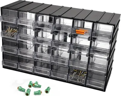 A storage organizer with multiple clear drawers filled with small items like screws and connectors, with a few green connectors scattered in the foreground.