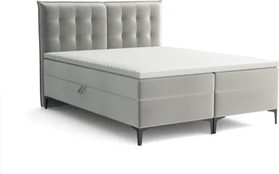 A studio shot of a gray boxspring bed with a white topper.