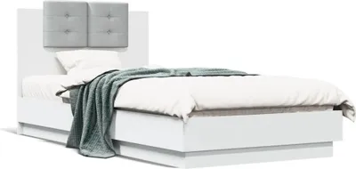 A white bed with a gray tufted headboard, a white duvet, and a teal throw blanket.
