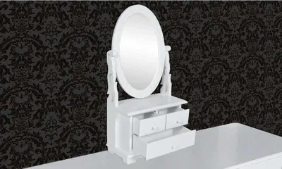 A white vanity table with an oval mirror and drawers is placed in front of a black damask wallpaper.