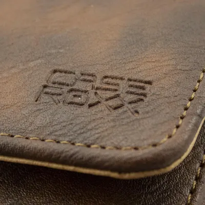 A close-up shot of a brown leather product with a logo embossed on it.
