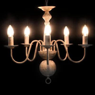 A white chandelier with five candle-shaped bulbs against a black background.