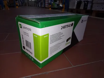 A product box for a Lexmark toner cartridge is placed on a tiled floor in what appears to be a warehouse or storage area.