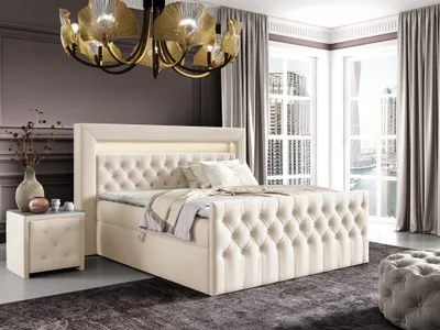 A luxurious bedroom with a large boxspring bed, nightstand, and a modern chandelier.