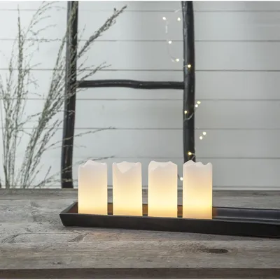 Four LED candles in a black tray on a wooden table, with a rustic ladder and branches in the background.