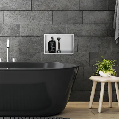 A modern bathroom with a black bathtub, a built-in niche with toiletries, and a small stool with a plant.