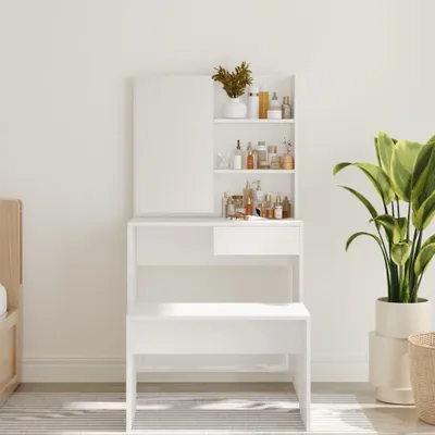 A white vanity table with a mirror and shelves filled with various bottles and containers, placed in a room with a plant and a bed frame visible.