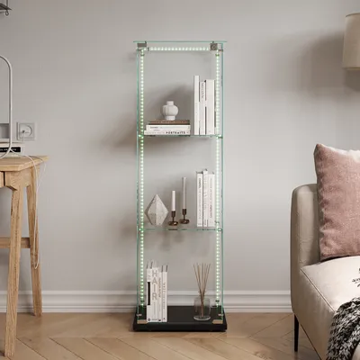 A glass display cabinet with LED lights, filled with books and decorative items, is placed in a living room next to a sofa and a desk.
