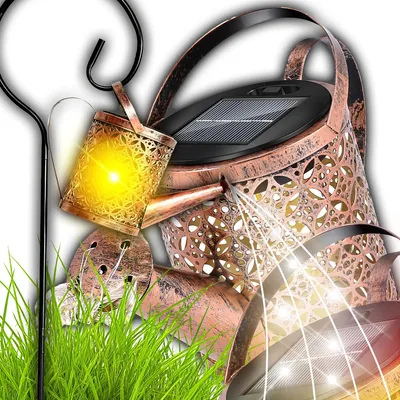 A close-up of solar-powered watering can garden lights, with grass in the foreground.
