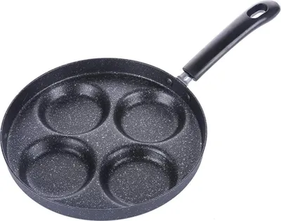 A black pancake pan with four circular indentations for cooking.