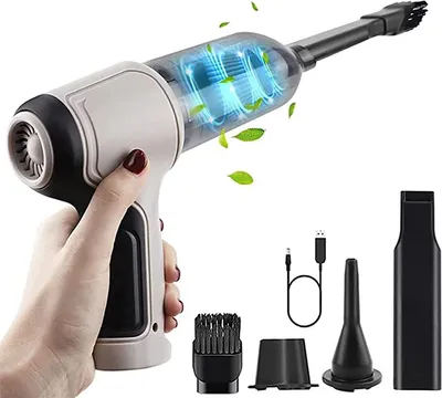 A hand holding a cordless mini vacuum cleaner with several attachments and a USB charging cable displayed separately.
