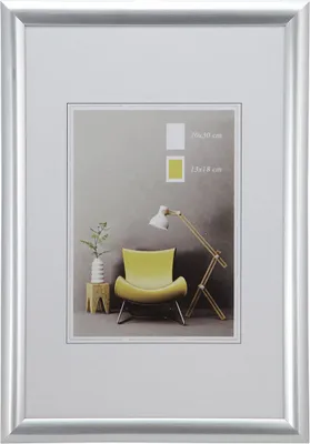 A silver picture frame with a mat and a sample image inside showing a chair and a lamp.