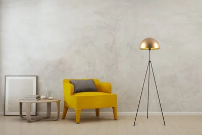 A modern living room scene with a yellow armchair, a side table with a framed picture and books, and a gold floor lamp.