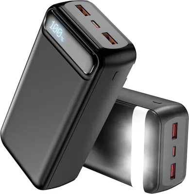 Two black power banks are shown against a white background. The front power bank is angled towards the viewer, displaying a digital screen showing '100%'. The second power bank is positioned behind and to the right of the first, also angled.