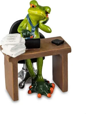 A figurine of a frog sitting at a desk, appearing to be working.