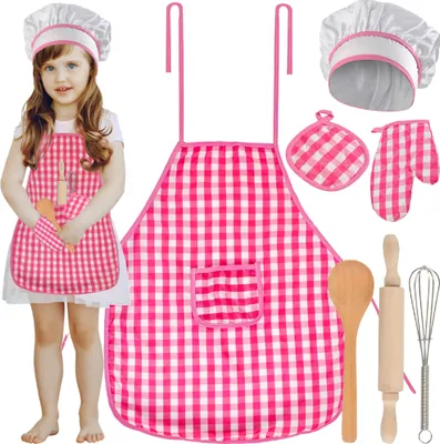 A young girl wearing a pink gingham chef's outfit, including a hat and apron, holding a toy rolling pin and oven mitt.