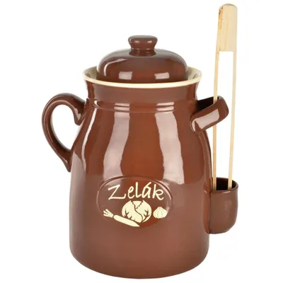 A brown ceramic jar with a lid and a wooden utensil holder attached, containing wooden tongs. The jar has an oval emblem with vegetables and text.