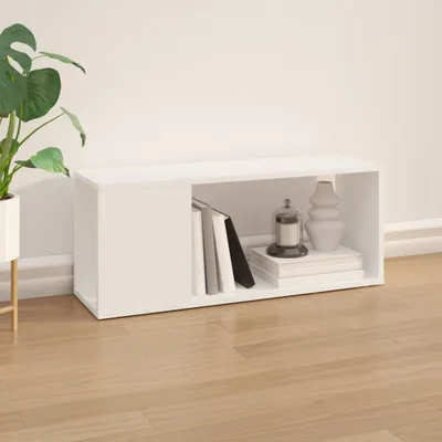 A white TV stand with books and decorative items on a wooden floor, next to a potted plant.