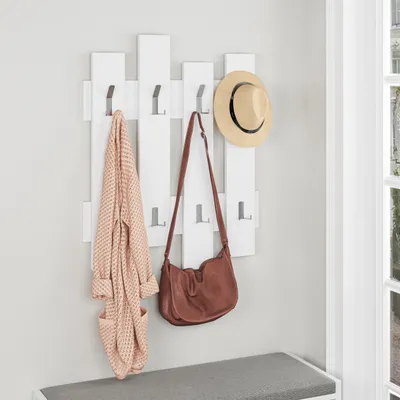 A hallway coat rack with a robe and handbag hanging on it, with a hat on top.