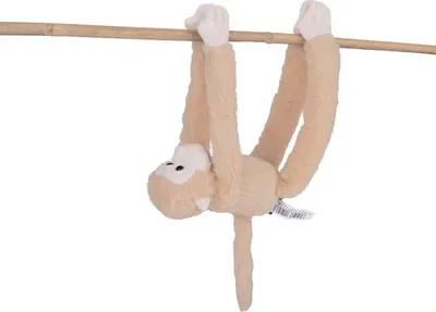 A plush monkey toy hanging from a wooden pole against a white background.