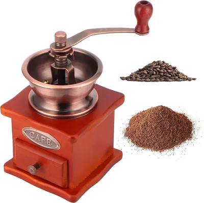 A vintage-style manual coffee grinder with a pile of coffee beans and ground coffee.