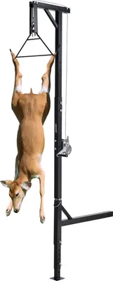 A deer is hoisted upside down on a black metal game hoist with a winch.