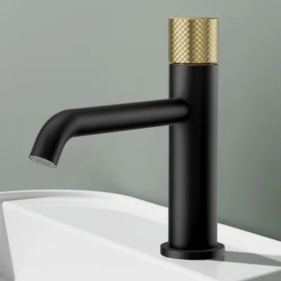 A black faucet with a gold textured top sits on a white sink.