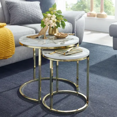 A living room setting with a sofa, a yellow throw blanket, and two nesting coffee tables with marble tops and gold metal frames.