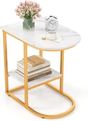 A modern side table with a marble-look top and gold metal legs, featuring two shelves. It is decorated with a vase of pink tulips, a white alarm clock, and a cup of coffee.
