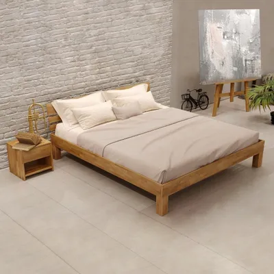 A wooden bed in a bedroom setting with a brick wall and a painting in the background.