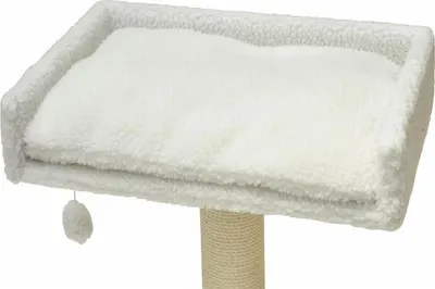 A close-up view of a white, fluffy cat bed with a small pom-pom toy hanging from the side, resting on a beige, rope-wrapped post.
