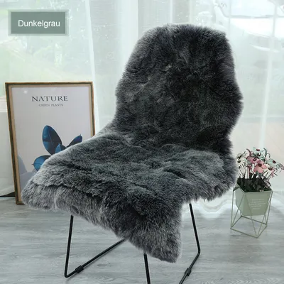 A dark gray faux fur rug draped over a chair, with a framed picture and a potted plant in the background.