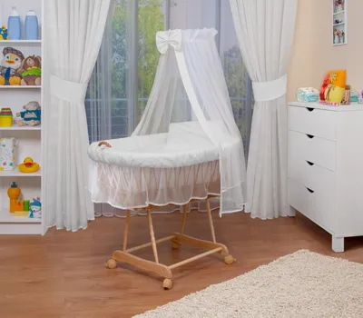 A baby bassinet set is displayed in a nursery setting, next to a white dresser and a bookshelf.