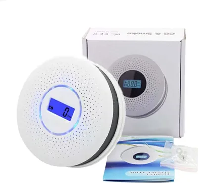 A white carbon monoxide and smoke detector is shown in front of its packaging.