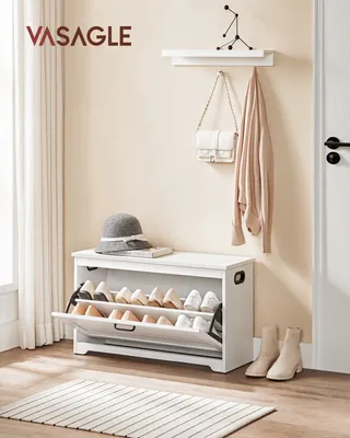 An entryway scene with a white shoe cabinet, hat, books, and a coat on a shelf.