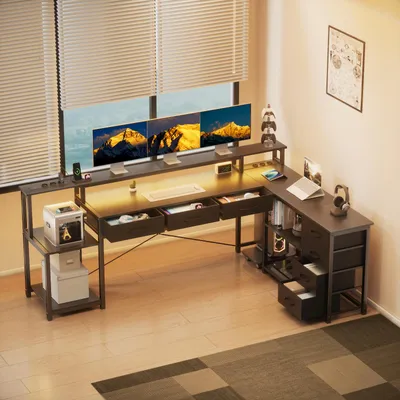 A modern L-shaped desk setup with multiple monitors, drawers, and shelving, positioned near a window.