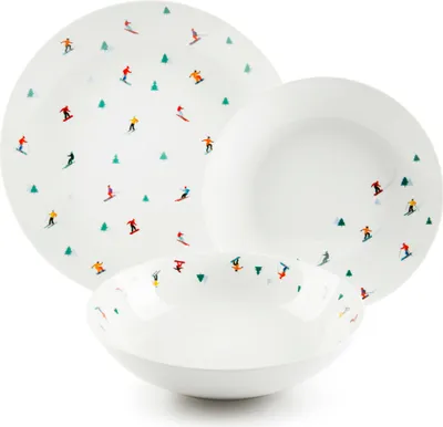 A set of white porcelain plates and bowls with a pattern of skiers and Christmas trees.