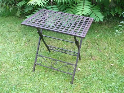 A folding metal table is placed on a grassy lawn with green foliage in the background.