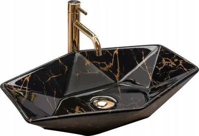 A black and gold marble-patterned ceramic sink with a gold faucet against a white background.